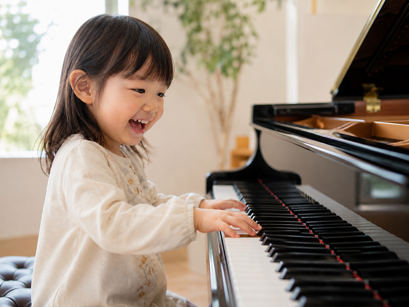 グランドピアノにふれて笑顔で音を楽しむお子さま