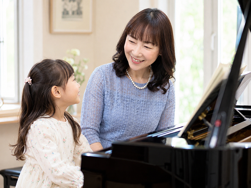 先生とお子さまが笑顔で向き合うピアノレッスンの様子